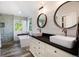 Well-lit main bathroom features double sinks, white cabinets, a large window, and a glass enclosed shower at 10028 Chelmsford Ter, Parker, CO 80134