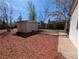 Wide shot of a backyard, showcasing red mulch and a storage shed with a concrete walkway at 992 Toledo St, Aurora, CO 80011