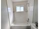 Bright bathroom featuring a clean white tub with white subway tile surround and a window for natural light at 992 Toledo St, Aurora, CO 80011