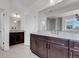 Vanity with double sinks, dark wood cabinets, granite countertops and a shower at 117 Nova Ct, Erie, CO 80516