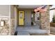 Inviting front porch with a bright yellow door, stone pillar, and an American flag waving above at 117 Nova Ct, Erie, CO 80516