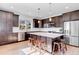 Modern kitchen with dark wood cabinets, a large center island, stainless steel appliances, and a tiled backsplash at 117 Nova Ct, Erie, CO 80516