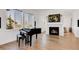 Elegant living room with a grand piano, fireplace, large windows, and hardwood flooring at 117 Nova Ct, Erie, CO 80516