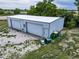 Exterior view of a large barn with garage doors, trash cans, and gravel lot at 14831 Riverdale Rd, Brighton, CO 80602