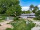 Exterior view of a home with mature trees and detached garages/outbuildings at 14831 Riverdale Rd, Brighton, CO 80602