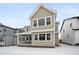 Two story home's exterior showcases neutral siding and ample windows, enhancing natural light, complemented by snowy landscaping at 16671 W 93Rd Ave, Arvada, CO 80007