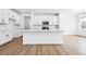 Modern kitchen featuring white cabinets, a spacious island, stainless steel appliances, and hardwood flooring at 16671 W 93Rd Ave, Arvada, CO 80007