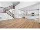 Open-concept living space featuring a staircase, hardwood floors, and a modern kitchen with white cabinetry at 16671 W 93Rd Ave, Arvada, CO 80007
