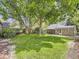 Lush backyard featuring green grass, large trees, patio set, white chair, and a wood fence at 3265 S Ogden St, Englewood, CO 80113