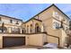 Multi-level townhome with tan exterior, arched entryways, and a two-car garage and steps leading to the front door at 150 S Harrison St # 9, Denver, CO 80209