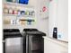 Modern laundry room featuring front loading washer and dryer units, ample shelving, and an on demand water heater at 2321 S Acoma St, Denver, CO 80223