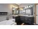 A primary bathroom showcases dual vanities with dark cabinets, decorative tile accents, and a soaking tub at 7909 Fairfax Ct, Niwot, CO 80503