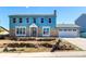 Two-story home with brick and blue siding, attached garage, and stone landscaping under a clear, blue sky at 2336 S Dawson Way, Aurora, CO 80014
