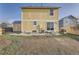 Home's backyard with grass, patio, yellow siding and a small shed on the left at 55410 E 27Th Pl, Strasburg, CO 80136
