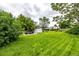 Expansive backyard featuring lush green grass, mature trees, patio with seating, and a storage shed for outdoor living at 11886 Birch Dr, Thornton, CO 80233