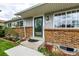Welcoming front entrance with brick detail, gray siding, and a well-manicured lawn at 11886 Birch Dr, Thornton, CO 80233