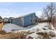 Exterior view of blue single-story home with a yard, snow, rock landscaping and wooden fence at 13151 Ivanhoe St, Thornton, CO 80602