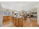 Open-concept kitchen with wood cabinetry, an island, hardwood floors, and a view of the dining area at 13151 Ivanhoe St, Thornton, CO 80602