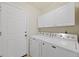 Functional laundry room with a full-size washer and dryer, plus storage cabinets at 13151 Ivanhoe St, Thornton, CO 80602