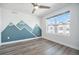 Bedroom featuring a modern mountain mural, a ceiling fan, and a large window offering neighborhood views at 3481 W 63Rd Ave, Denver, CO 80221