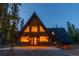 Charming A-frame home with a unique architectural design and inviting exterior lighting at twilight at 297 Robertson Ln, Breckenridge, CO 80424