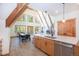 A-frame living area featuring exposed beams, wood floors, fireplace, dining table, and access to kitchen at 297 Robertson Ln, Breckenridge, CO 80424