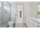 White bathroom with tiled shower, toilet, vanity, white fixtures and a doorway to the bedroom at 6393 S Jamaica Ct, Englewood, CO 80111