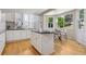 Open kitchen featuring white cabinets, granite countertops, an island, and a sunny breakfast nook with large windows at 6393 S Jamaica Ct, Englewood, CO 80111