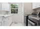 Spacious laundry room featuring a modern washer/dryer unit, white cabinets, and a window at 6393 S Jamaica Ct, Englewood, CO 80111