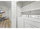 A clean laundry room featuring a stacked washer and dryer, white walls and shelves at 8200 E 8Th Ave # 5-204, Denver, CO 80230