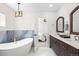 Bright bathroom featuring a soaking tub, a double vanity with dark cabinets, and modern light fixtures at 4645 E Florida Ave, Denver, CO 80222
