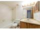 Clean bathroom with tiled tub, standard toilet, and wooden vanity at 1301 S Cathay Ct # 104, Aurora, CO 80017