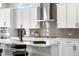 Bright kitchen featuring white cabinets, subway tile backsplash, and stainless steel vent hood at 5597 Pinto Valley St, Parker, CO 80134