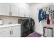 A modern laundry room is equipped with a sink, washer, dryer, storage, and hanging area at 5597 Pinto Valley St, Parker, CO 80134