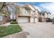 View of townhomes with brick facade, light beige siding and two-car garage, as seen from the street at 341 Granby Way # A, Aurora, CO 80011