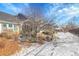 Backyard features snow-dusted shrubbery, trees, and a quaint patio for outdoor enjoyment at 7633 S Addison Way, Aurora, CO 80016