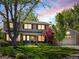 Charming two-story home with a well-manicured lawn, mature trees, and red shutters at dusk at 4175 S Sidney Ct, Denver, CO 80237