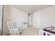 Bedroom features a rocking chair, crib, and bright windows, making it a cozy and inviting space for a baby at 10553 Xenia Ct, Commerce City, CO 80640