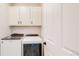 Functional laundry room with modern, white appliances and overhead storage at 10553 Xenia Ct, Commerce City, CO 80640