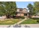 Charming two-story home features a brick facade, manicured lawn, and mature trees at 10700 Addison Ct, Highlands Ranch, CO 80126