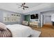 A bright main bedroom with a large bed, tray ceiling with ceiling fan, and a seating area with decorative accent wall at 10700 Addison Ct, Highlands Ranch, CO 80126