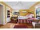A bright bedroom with yellow walls, hardwood floors, and a bed with striped linens at 357 Birch St, Denver, CO 80220