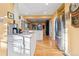 Open kitchen with stainless steel refrigerator, white cabinets, barstool seating, and hardwood floors at 357 Birch St, Denver, CO 80220