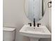 Modern half-bathroom with a sleek pedestal sink and a minimalist mirror at 8658 Pennycress Dr, Littleton, CO 80125
