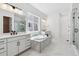 Bright bathroom featuring a modern soaking tub and dual vanities, illuminated by natural light from a window at 8658 Pennycress Dr, Littleton, CO 80125