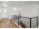 Bright hallway with wood floors, metal railing, a white door, and recessed lighting at 8658 Pennycress Dr, Littleton, CO 80125