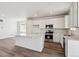 Bright kitchen with white cabinetry, stainless appliances, a large island, and light wood floors for a modern design at 9151 Telluride Ct, Commerce City, CO 80022