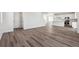 Open-concept area showing hardwood floors and a kitchen with white cabinetry, stainless appliances, and modern lighting at 9151 Telluride Ct, Commerce City, CO 80022