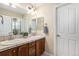 Bright bathroom featuring double sinks, tiled countertops, dark wood cabinets, and a large mirror at 26861 E Clifton Dr, Aurora, CO 80016