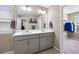 Bathroom featuring dual sinks, large mirror, quartz countertop, gray cabinetry, and closet access at 14100 Shasta Daisy St, Parker, CO 80134